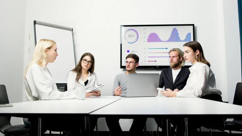 Tim profesional mendiskusikan deliverables dan data proyek dalam rapat bisnis